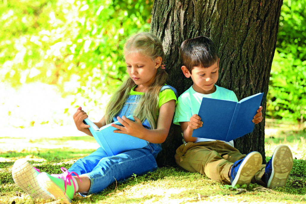 Lesende Kinder vor einem Baum