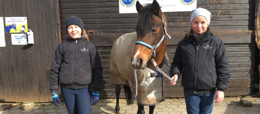 Zwei Mädchen stehen neben einem Pony