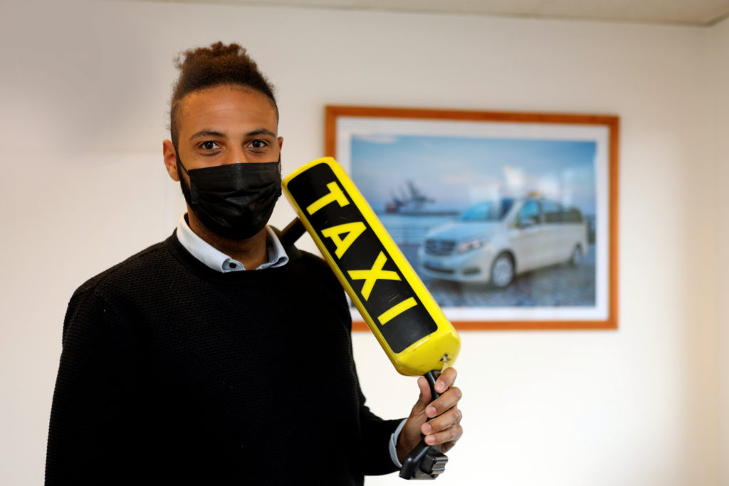 Taxifahrer Fabian M. mit Maske und Taxischild