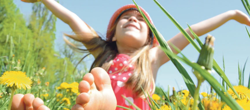 Kind sitzt in der Blumenwiese