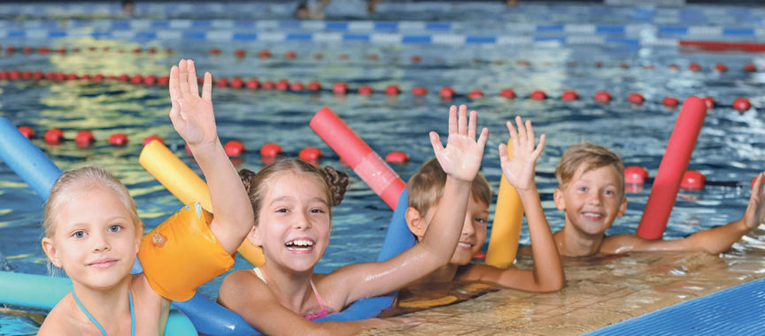 Little kids with swimming noodles in indoor pool